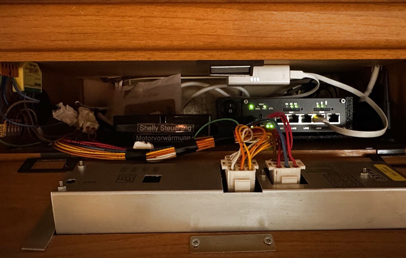 Der Router im Klappfach hinter der originalen Wohnmobil-Bedienung, daneben Kabelbäume und ein Schaltmodul
